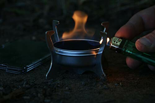 Hand lighting a portable camping stove with a lighter.