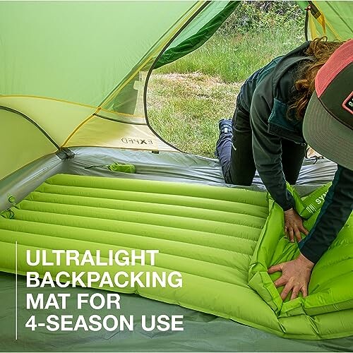 Person setting up an ultralight backpacking mat inside a tent